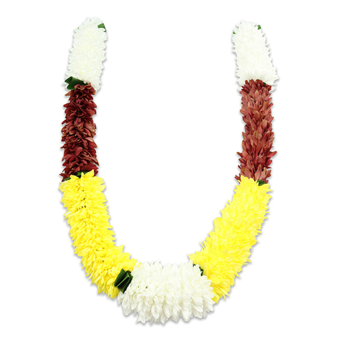 Rendered against a crisp white background, this U-shaped mala reads as a study in texture and cultural meaning, every inch of its surface composed of thousands of tiny fabric petals. At the top of each symmetrical arm a dense, cylindrical cluster of creamy white petals-carefully formed to mimic small chrysanthemums or jasmine-creates a light, ethereal opening. That white immediately yields to a concentrated band of maroon or deep reddish-brown, the petals packed so closely they form a velvet-like plane. The maroon segments then transition into the garland's most expansive element: a long, luminous sweep of yellow flowers whose plush, layered petals build the volume of the U and lend an energetic, welcoming brightness. Where the two yellow arms meet, a generous, central cluster of pure white blooms forms a visual clasp; its chrysanthemum-like textures mirror the top segments and provide compositional balance. Small dark-green leaf accents are strategically placed between colour blocks, especially where yellow meets white, offering a touch of botanical realism and calming contrast. The construction suggests a durable, ceremonial object-meant to be carried, draped, or displayed during Hindu poojas, temple offerings, weddings, and festivals such as Diwali and Holi-while the chosen palette speaks of purity, prosperity, and devotion. I imagine this garland draped at a Canonbury doorway, hung above a home shrine near Upper Street, or used to honour guests at a local community mandap close to Chapel Market; it's an object of careful artisanry, both decorative and reverential in purpose.