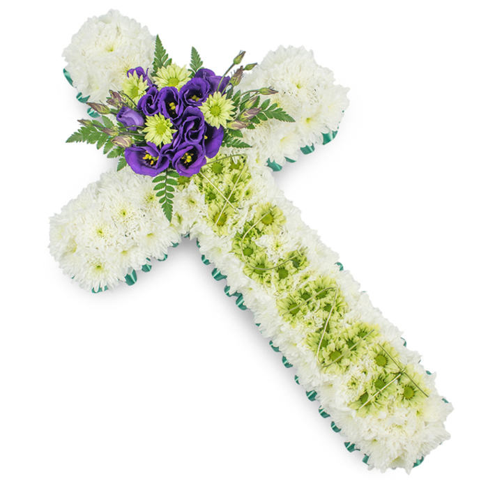 This image shows an elegantly designed floral cross, carefully crafted as a funeral or memorial tribute, presented on a clear white background that allows every detail to stand out. The main body of the cross, including both arms and the full vertical length, is closely packed with snowy white spray chrysanthemums, their tiny petals overlapping to form a continuous, padded surface that feels soft and serene, reminiscent of gentle clouds drifting above Canonbury's rooftops. Along the outer edge, a sharply defined border of bright green ribbon or neatly arranged foliage runs uninterrupted, outlining the cross with a fresh, vibrant frame that subtly lifts the design. Centrally positioned down the vertical arm is a wide panel of lime green button chrysanthemums, their compact, button-like blooms forming a smooth band of colour that contrasts with the surrounding white. Fine strands of pale green decorative wire have been placed over this section in a loose diamond or lattice pattern, adding a touch of contemporary detail and a sense of careful craftsmanship without overwhelming the flowers. At the junction of the cross's arms, a rich focal point is created from deep purple lisianthus blossoms, their velvety, ruffled petals unfolding around dark centres. These are interspersed with bright lime green button chrysanthemums that echo the central band below. Dark green fern fronds and gracefully arranged foliage fan out from behind, softening the geometry and giving the tribute a natural, garden-like depth. The overall effect is peaceful, dignified, and reverent, a floral cross perfectly suited to Christian funerals, church services, or graveside farewells in Canonbury, conveying love, sympathy, and a promise of remembrance.
