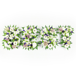 This horizontally arranged floral tribute spells out D-A-D with a composed, soothing palette of whites, purples, and fresh greens, presented against a bright white backdrop. Each letter is a compact, plush composition: ivory gerberas with rounded faces and subtle dark eyes; billowy white carnations and creamy lisianthus that add soft, layered volumes; and velvety chrysanthemums in pale tones that ground the shapes with quiet presence. Soft mauve and lavender roses are tucked into the letters and paired with deeper violet statice or filler blooms, creating intervals of reflective colour that feel respectful rather than ornate. Lush fern fronds trace and define the edges of each character, their feathery texture lending a gentle movement as if a low breeze had passed over them, while clusters of small green button chrysanthemums punctuate the interiors with fresh, verdant contrast. A sturdy dark foam or backing peeks through in places, giving the letters structure and clear legibility while the flowers seem to sit just above it. The lighting is soft and even, bringing out the satin sheen of the petals and the cool, calming scent of white blooms blended with green foliage. This arrangement carries the quiet restraint of a sympathy piece intended for a father's service-honouring memory with simplicity and care. As a local Canonbury-style design, it reflects the neighbourhood's preference for thoughtful, understated tributes often requested by families from Essex Road to Upper Street.