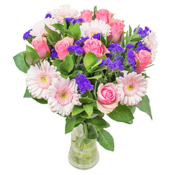 As seen from the warm, artisan worktables of Canonbury Flowers, this radiant bouquet captures the interplay of colour and light that defines our local aesthetic. Delicate gerberas in soft blush tones and timeless pink roses mingle at the bouquet's heart, their layered petals forming ripples of gentle pink that recall the calm mornings over Canonbury Square. Vivid purple stems-likely statice-leap in and out of view, giving delightful punctuation amid the softness, while glossy, abundant green leaves anchor the arrangement in lush freshness. The glass vase is spare and classic, allowing stems and water to show clearly, reminiscent of easy elegance found in many a Canonbury windowsill. Every element is placed with the care and precision of a florist who knows the subtle joys this community values: moments of optimism, graceful beauty, and thoughtfulness. Whether designed as a stylish get-well surprise for a neighbour on Douglas Road, or as a luminous accent for a peaceful sitting room, this bouquet is a true celebration of local craftsmanship, radiating hope and quiet delight.