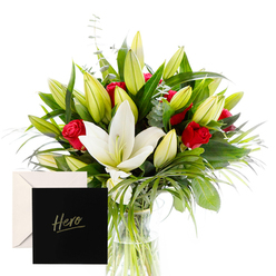 Canonbury Flowers offers a refined bouquet that feels like a portrait of sophistication and emotion, carefully composed to invite admiration and comfort. At the center, white lilies stand tall, their large trumpet blooms opening to reveal creamy, softly scented interiors, while slender green spears and curls frame them with architectural grace. Scattered among them, red roses cluster with a confident sigh, their velvety petals releasing a gentle, lingering fragrance that mingles with the lilies in a dewy, hypnotic chorus. A bouquet of unopened buds promises beauty yet to come, a quiet note of hope and ongoing celebration. The arrangement glows in bright, clear light, every leaf and petal distinctly outlined in freshness. A tasteful card marked Hero accompanies the gift, making it an ideal expression of thanks or remembrance-a floral embrace for someone whose spirit inspires.

Placed in a tidy corner of a Canonbury home near New North Road, this composition feels at once intimate and elevated, suitable for a desk at work, a bedside table in a patient room, or a dining table during a small gathering. It is designed for same-day delivery across Canonbury, Islington, and nearby districts, delivering warmth with efficiency. The natural arrangement leans toward quiet restraint, with rich greens providing a cooling backdrop to the bright whites and strong reds. It speaks of strength, gratitude, and shared achievement, a thoughtful gesture from Canonbury Flowers to a neighbour who has made a difference in the local community.
