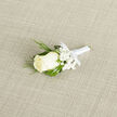 At the centre of this boutonniere rests a pristine ivory rosebud, its petals layered with a velvet softness that invites a closer look. Small clusters of cloud-like baby's breath cradle the bloom, their tiny white stars softening the composition, while slender, feathery sprigs of dark green foliage-reminiscent of cedar-reach outward, providing a graceful, textured silhouette against broader, deep-green leaves that offer a steady, structural backdrop. The stems are wrapped in a satin-white ribbon, its sheen discreet and refined, tied into a tidy bow that anchors the arrangement and speaks to meticulous hand-tying techniques. Placed on a subtle light-beige woven fabric, the boutonniere's tones are amplified: the creamy petals, bright white gypsophila, and varying greens read with clarity and calm under soft, diffused light.
As a florist who daily walks Canonbury's streets and sources seasonal stems from nearby markets, I find this small piece particularly suited to intimate ceremonies around Essex Road and the Angel. It carries a delicate fragrance-fresh, faintly floral-evoking the early hours before a celebration. Practical yet poetic, the boutonniere is cut and prepared to last through vows and photographs, intended to be worn close to the heart. Available through Canonbury Flowers for local occasions, it's a traditional, timeless choice that balances purity and craftsmanship, perfect for grooms, ushers, or anyone who prefers quiet sophistication over flourish.