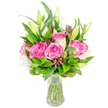 A bright, joyful bouquet of deep pink roses and white lilies sits in a simple clear glass vase, photographed against a clean white background so every petal and leaf is easy to imagine. The roses dominate with fully opened heads in shades from soft blush to saturated fuchsia, their velvety layers folding inward and catching the light like satin; nearby, tall white lily buds lean outward, some tightly furled and others just softening to reveal pure white trumpets and the faint green of their throats. A generous sweep of mixed greenery-broad glossy leaves, pointed laurel-like blades and finer, feathery sprigs-envelops the blooms, creating a lush, rounded silhouette that makes the pinks and whites sing. Small accents of darker burgundy or reddish-brown buds and foliage are threaded through the arrangement, adding a subtle shadowed depth that catches the eye and gives texture when seen up close.

Through the transparent vase the neatly trimmed green stems are visible, submerged in clear water that reflects the studio light and reinforces the sense of freshness; the vase's gently tapered base and slightly flared rim keep the bouquet composed and upright. The scent, if you could smell it, would be a soft blend of rose sweetness with the delicate, powdery perfume of lilies-comforting and celebratory at once. As a local florist might suggest for Canonbury living rooms or a table at Canonbury Square, this arrangement reads as both an elegant gift and a welcoming centrepiece, suitable for birthdays, anniversaries or simply to lift the spirit of a neighbour. The composition balances romance and restraint, offering a timeless floral portrait that feels hand-crafted and ready for delivery across Canonbury and the surrounding Islington streets.