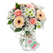 A radiant mixed bouquet unfolds in the sunlit calm of a Canonbury studio, bathed in soft daylight that magnifies every nuance. At its core, lush peach-pink roses swirl open, their velvety petals delicately embracing memories of springtime strolls past leafy Islington greens. Flanking these central roses, glowing peach gerberas with velvety chocolate centres bring cheerful brightness, their symmetry and simplicity contrasting beautifully with the layered complexity of surrounding blooms. Wispy white baby's breath floats like gentle mist between flowers, infusing a sense of airy movement, while neat clusters of white chrysanthemums with fresh green-yellow centres add substance and crispness. Deep green eucalyptus leaves are thoughtfully tucked throughout, their cool aroma mingling with the fragrance of fresh petals, echoing the scent of gardens found off Canonbury Road. The clear textured glass vase, with its softly flared base, cradles the bouquet as water sparkles through the crisscrossed stems. A slender raffia bow secures a white rectangular tag at the neck-its blank space awaiting a loving message for the fortunate recipient. With an aura of authentic craftsmanship and heartfelt care, this bouquet feels perfect for moments of appreciation or celebration, ready for seamless flower delivery throughout Canonbury and nearby Angel, and certain to bring a breath of freshness wherever it arrives.