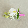 This image shows an elegant boutonniere carefully composed on a backdrop of subtly textured, oatmeal-coloured linen, the natural fabric giving a calm, modern canvas that highlights every floral detail. At the heart of the design sits a single white Phalaenopsis orchid, its petals wide, silky, and beautifully symmetrical, opening to reveal a softly patterned centre where yellow-orange and the faintest blush of pink meet in intricate curves. Encircling the orchid is a delicate collar of white Gypsophila, or baby's breath, the tiny clustered blossoms appearing like drifting clouds, adding volume without weight and bringing a dreamy, romantic softness. Threaded between these are slender, fresh green leaves, their clean lines and luminous colour offering a striking counterpoint to the pure whites, grounding the boutonniere with a touch of garden-like vitality. To one side, a short length of orchid stem extends outward, bearing three rounded, pale green buds that have yet to open, suggesting new beginnings and adding depth and subtle movement to the composition. The stem is tightly finished with a bright pink satin ribbon, its sheen catching the light as it is tied into a neat, compact bow, tails trimmed to keep the silhouette refined. The pink ribbon brings a joyful splash of colour that feels contemporary yet timeless. As a Canonbury florist, I picture this boutonniere being chosen for a wedding at a local town-hall ceremony or a celebration after a stroll through nearby New River Walk, ready to be pinned to a suit jacket as a small but meaningful expression of style, love, and care.