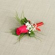 A single, carefully crafted boutonnière is laid diagonally across a softly textured, light beige fabric, reminiscent of natural linen you might find in a Canonbury townhouse off Essex Road. At its heart sits a tightly furled rosebud in vivid fuchsia or deep crimson-pink, the petals smooth and velvety, cupped closely together so the bloom feels full of quiet anticipation. Clusters of tiny white baby's breath surround the rose, each minuscule blossom like a dot of cloud against the rich colour, giving the arrangement a soft, airy halo. Behind and around the central flower, bright green, feathery foliage fans out in gentle arcs, as if catching a breeze drifting over New River Walk: fine, grass-like fronds and a few slightly broader green leaves add depth, movement, and a freshly picked feel. The stems are gathered neatly and wrapped in a narrow band of glossy red satin ribbon, wound firmly but delicately to create a smooth, polished handle that hints at celebration and care. The light falls evenly across the image, illuminating the subtle sheen of the ribbon, the crisp whiteness of the gypsophila, and the saturated glow of the rose, so every texture-from the linen backdrop to the ferny greenery-feels tangible. This elegant buttonhole, designed for a wedding, prom, or formal evening out near Upper Street or along the tree-lined roads of Canonbury, conveys romance and poise, as though it is ready to be pinned to a lapel just moments before vows are spoken or a special occasion begins.