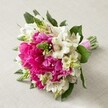Resting gently on a light, creamy fabric, this compact yet naturally abundant hand-tied bouquet radiates joy and sophistication, a true reflection of Canonbury's neighbourhood charm. Dominated by voluptuous, fully opened fuchsia peonies-each one a whirl of ruffled satin petals bathed in soft daylight-the bouquet feels both lively and inviting. Complementing these striking pink blossoms are clusters of pristine white Alstroemeria, their narrow petals subtly etched with maroon mottling, offering a crisp, elegant contrast to the peonies' lavish hue. Throughout the arrangement, slender, bright green floral spikes-possibly Hyacinth buds or Veronica-emerge, lending spirited verticality and contemporary flair. Lower in the bouquet, small, creamy white filler flowers with gentle, bell-shaped forms contribute a delicate airiness, while deep green foliage provides a verdant anchor, enhancing the interplay of colour and light. The stems are meticulously bound with a shiny pink satin ribbon, suggesting the bouquet's suitability as a cherished bridal accessory or a celebratory gift. Presented in natural light evocative of Canonbury's serene mornings, the entire floral display evokes a sense of hopeful new beginnings, fond memories, and the artistry of a dedicated local florist. Whether destined for a wedding in leafy Islington or a fresh addition to a home on Mildmay Avenue, this arrangement celebrates colour, harmony, and finely honed floral expertise.