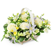 A tranquil funeral flower basket is presented against a spotless white background, the neutral setting allowing its soft colours and thoughtful composition to speak clearly. The basket is crafted from pale, almost white wicker, its weave fine and even, and its shape an elegant oval that cradles the flowers while a matching handle arches gently above, reminiscent of a comforting arm. Inside, the arrangement is densely yet carefully packed, forming a rounded, harmonious mound of blooms. Dominating the piece are large, open roses in creamy white, their velvety petals layered in generous spirals that evoke tenderness, reverence, and quiet love. Woven between them are delicate clematis flowers in pale lavender and light periwinkle shades, their star-shaped petals stretching outward around vivid yellow-green centers, adding a note of soft colour that remains respectful and serene. Smaller white and pale yellow freesia-like blossoms cluster in pockets throughout, some fully opened, others still in symbolic buds, giving the basket a gentle rhythm of shapes and a sense of time passing. Bright yet delicate yellow accents appear here and there, providing an uplifting touch without disrupting the calm. All of this is supported by a rich base of dark green foliage, with broad, glossy leaves and finer stems creating depth and contrast, like the layered greenery in Canonbury's quiet gardens. The composition feels like the work of a skilled local florist, carefully designed for memorial services, funeral tributes, or sympathy deliveries across Canonbury, where the intent is to offer solace, dignity, and a softly shining gesture of remembrance.
