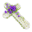 A large floral cross lies flat against a spotless white background, photographed from above so that its serene, symmetrical form fills the frame. The entire body of the cross is densely padded with immaculate white spray chrysanthemums, arranged petal to petal in a thick carpet of blooms. Their petals look soft and cool, with small pale green eyes adding the faintest whisper of colour, like dew on winter grass. Around the perimeter of the cross runs a slim band of lime-green ribbon, sharply edged and neatly fixed, offering a delicate contrast that outlines the design and brings a touch of springlike brightness. At the central meeting point of the cross arms, a lush cluster of royal purple lisianthus forms a striking focal point. These richly coloured flowers, some fully open and others still in bud, curl and fold into one another, their velvety petals deepening in tone toward the centre of each bloom. Light, feathery foliage and tiny complementary fillers thread between the lisianthus heads, adding natural movement and texture. From this focal cluster, a graceful line of additional lisianthus blooms and buds trails down the lower arm of the cross, set on a diagonal that guides the eye gently from the heart of the piece outward. A soft shadow beneath the design helps you sense its thickness and the careful layering of each flower. Evoking the quiet streets and hidden gardens of Canonbury, this cross feels deeply reflective and is perfectly suited to a church funeral, memorial service, or graveside tribute where faith, remembrance, and peace are at the forefront.