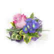 Against a clean white backdrop, this compact corsage reads like a little portrait of summer evenings in Canonbury: a single elegant rose takes centre stage, its petals graduating from a soft lavender-pink at the heart to a vivid fuchsia at the outer edges, the velvety folds catching a gentle, natural light. To the right, a cluster of indigo-purple florets-suggestive of hydrangea or periwinkle-brings a jewel-like contrast, each tiny blossom marked by bright blue and lime-yellow centres that twinkle like sunlit dewdrops. The blooms are cradled by a studied chorus of foliage: broad, variegated ivy leaves with deep emerald centres and warm golden-yellow margins give solidity and a classic silhouette; slender, silvery-green leaves-reminiscent of lavender foliage-soften the palette with muted texture; and a sculptural striped leaf of green and cream curls gracefully, lending a contemporary twist.

Delicate, airy sprigs of lighter green-similar to asparagus fern-thread through the composition, adding a sense of motion and breath. Beneath, an intricate web-like layer of dark purple mesh peeks out, its open weave creating depth and a subtle, modern shimmer. On the lower right, a short strand of lustrous white pearls suggests the attachment or wristlet, catching highlights against the white ground. The overall impression is romantic yet modern: tactile, fragrant, and meticulously balanced-ideal for weddings, prom or milestone celebrations. The corsage's restrained palette and thoughtful textures invite both sight and touch, offering the quiet pleasure of a handcrafted floral accessory ready to accompany someone along Canonbury's leafy lanes or to a celebration at nearby Canonbury Square.